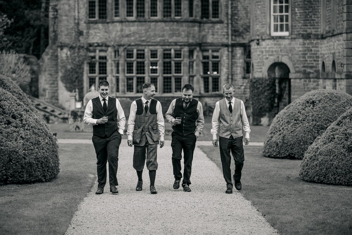 groomsmen walk through the garden at Tissington Hall