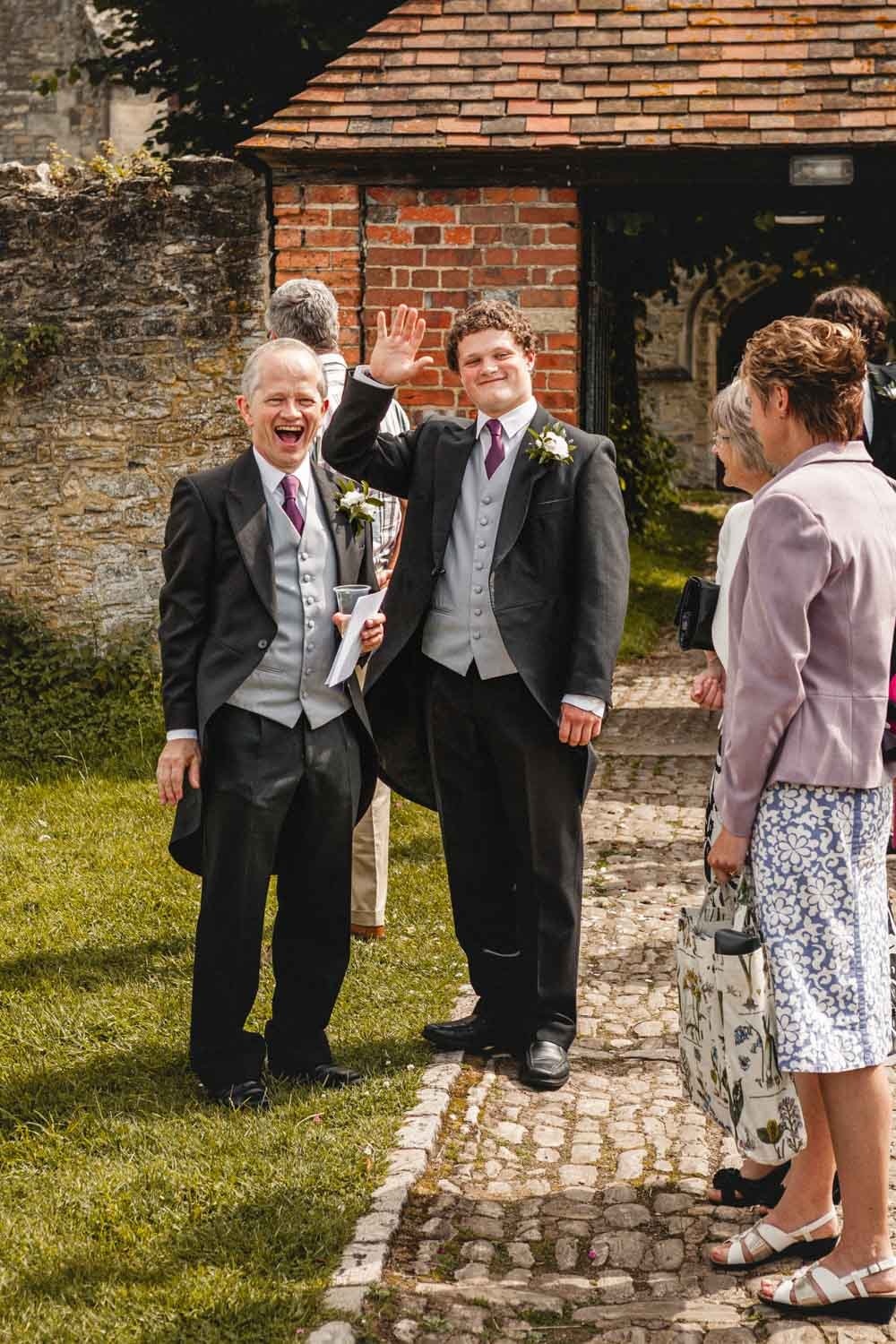 father and brother of the bride greet guests outside church
