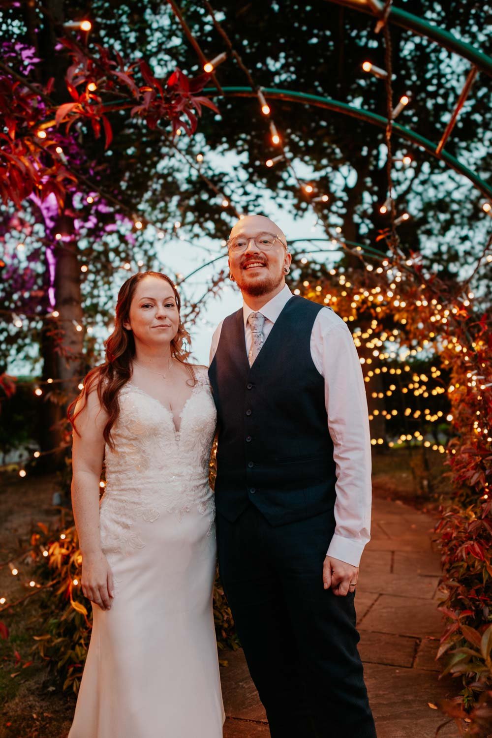 newlyweds in garden with fairy lights at twilight