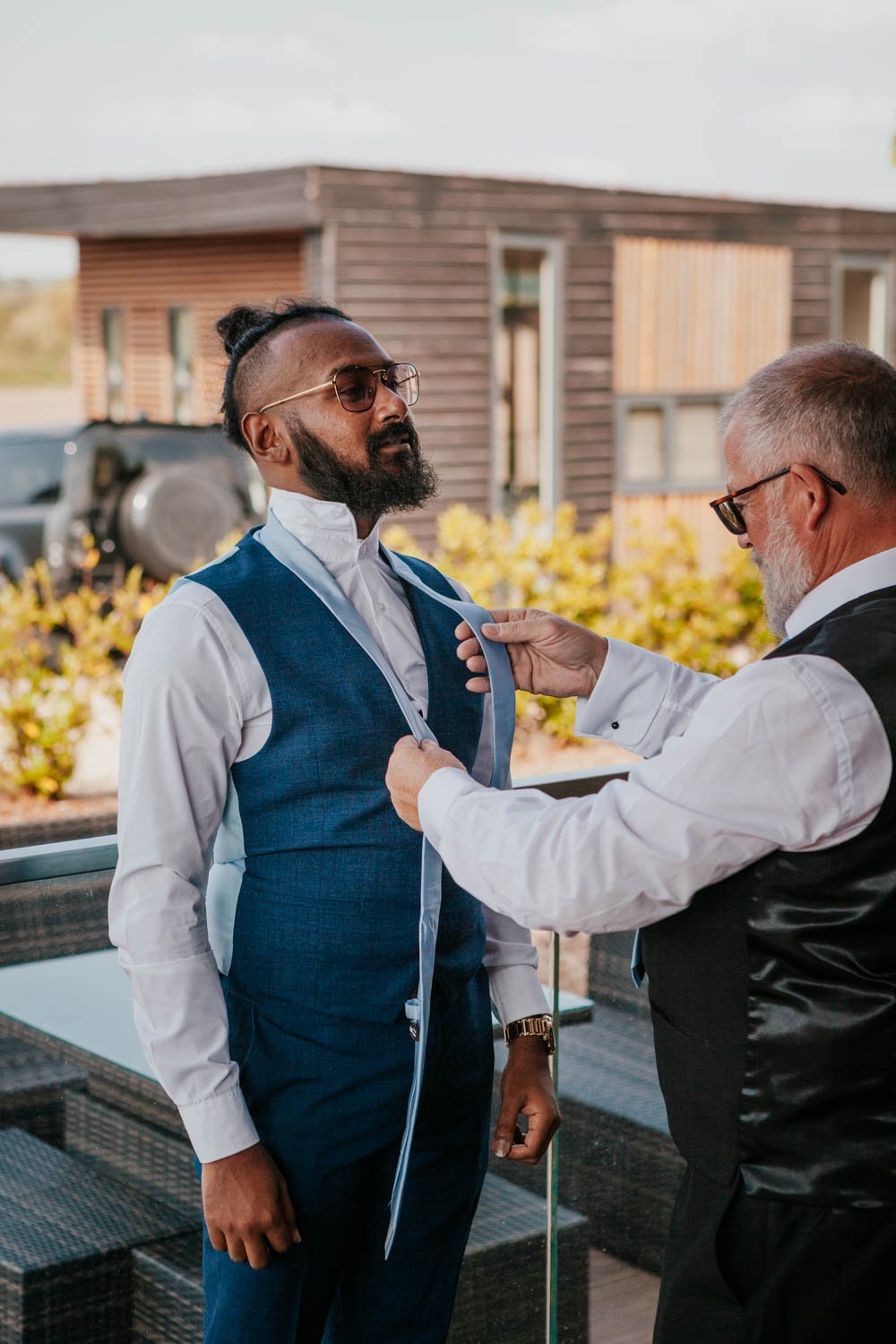 Father of the bride helps a groomsman with his tie at Goosedale lodge