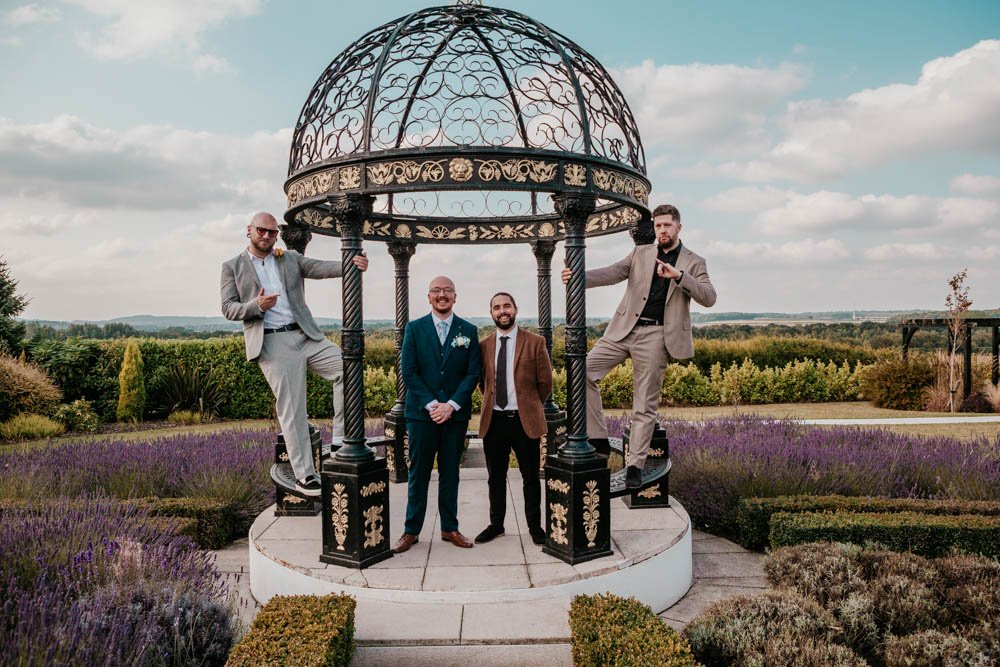 groomsmen climb on a pergola in the lavender garden at Goosedale