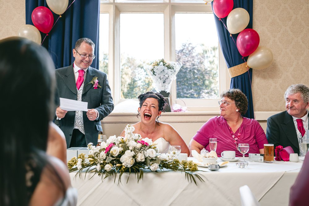 bride laughs hysterically during wedding speeches