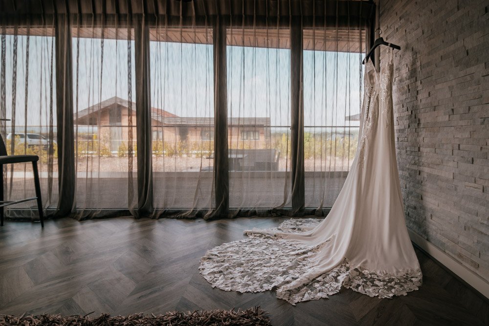wedding dress hangs in front of window