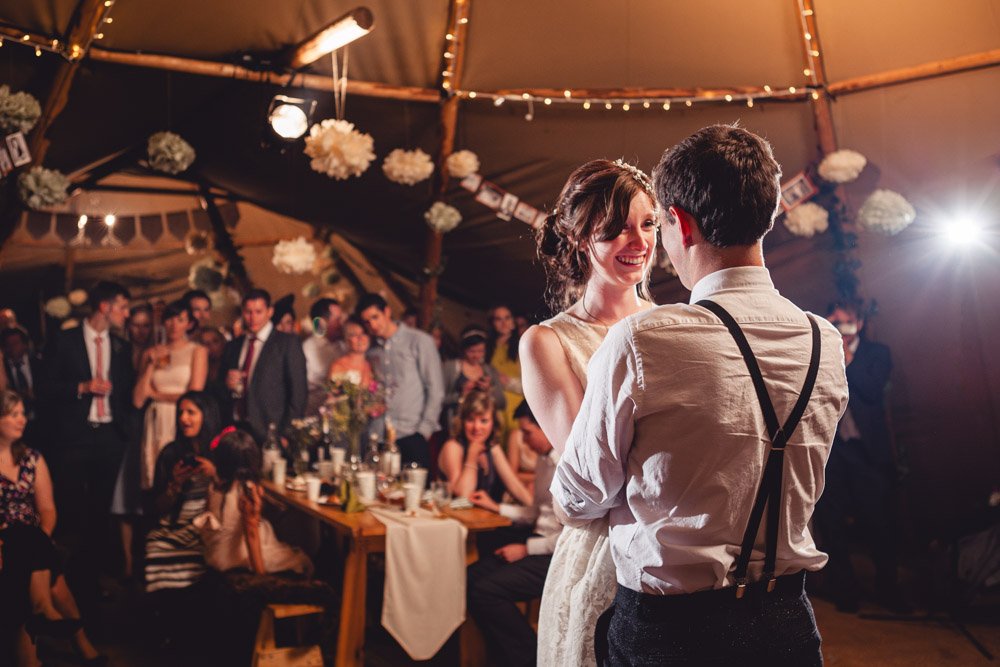 bride and groom first dance in a tipi wedding, as guests watch
