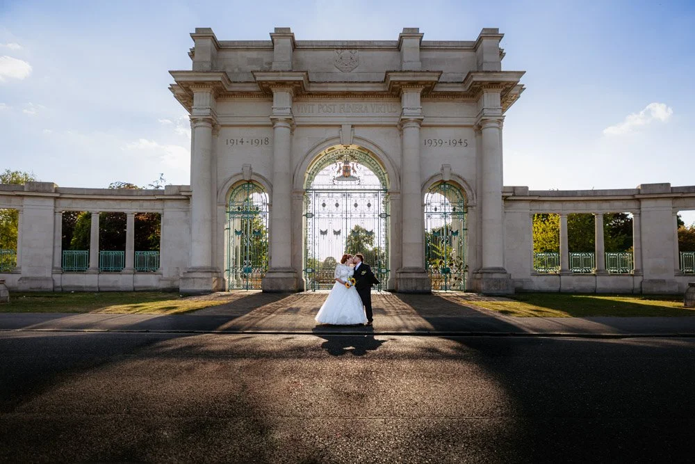bride and groom kiss in front of memorial gardens at Nottingham Embankment