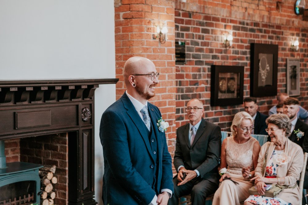 groom smiles in Goosedale Crystal Hall as he waits for bride