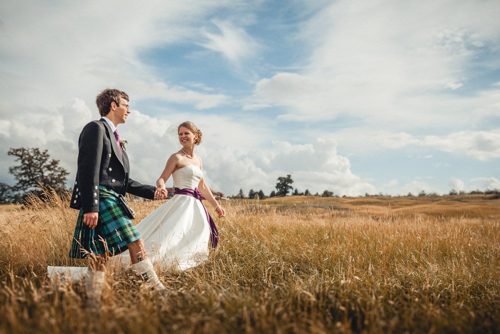 bride and groom walk across grassy meadow at Oxfordshire Golf Course