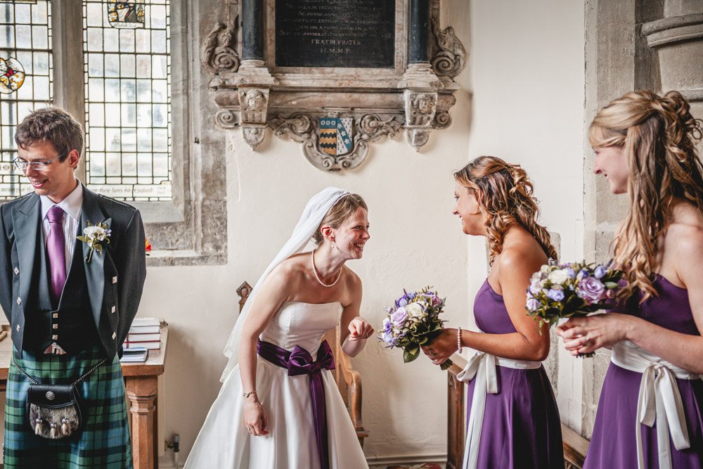 bride laughs with bridesmaids inside church