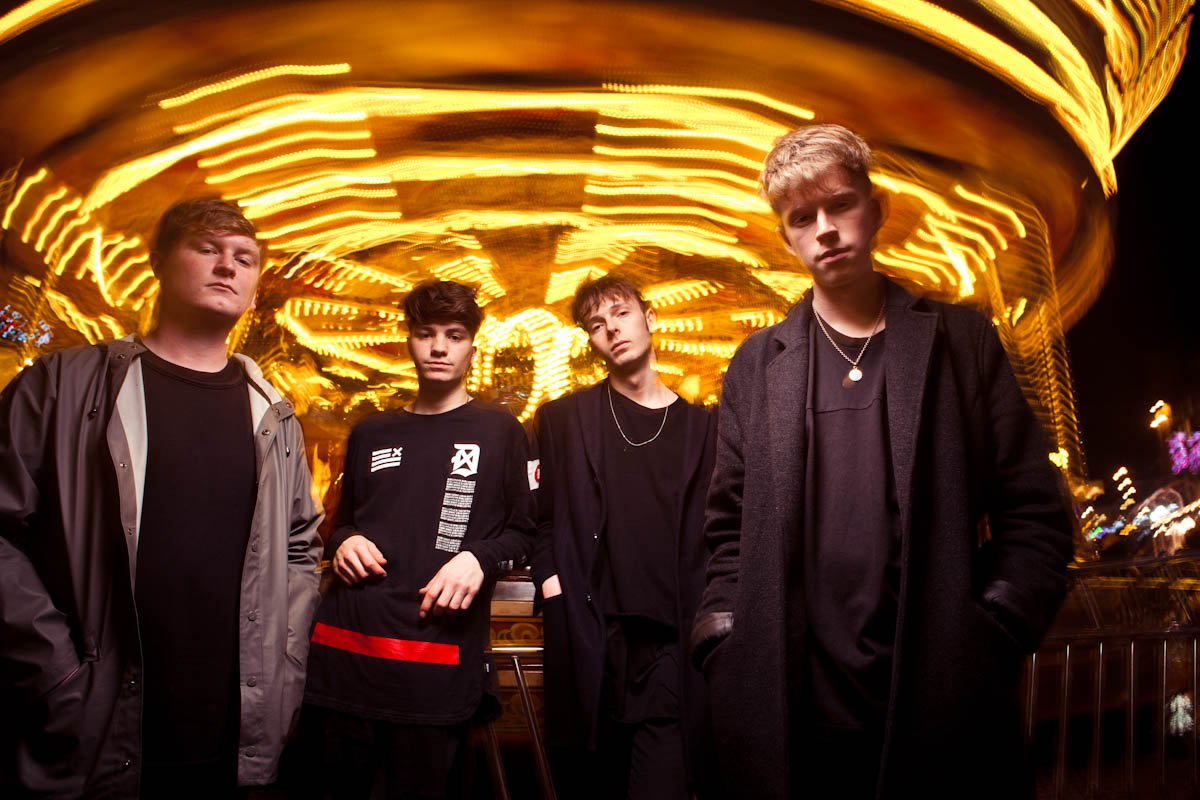 Worthing band Noisy stand in front of a blurry merry-go-round