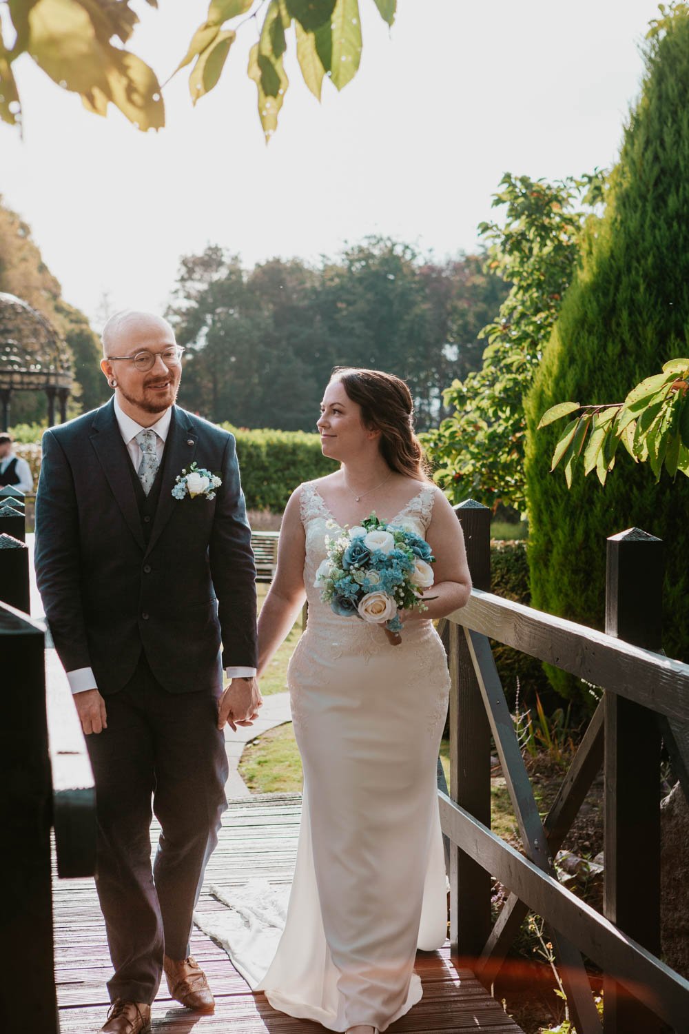 bride and groom walk across a bridge
