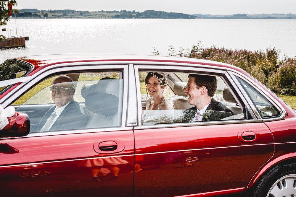 Bride and groom in a luxury Jaguar car next to Rutland Water