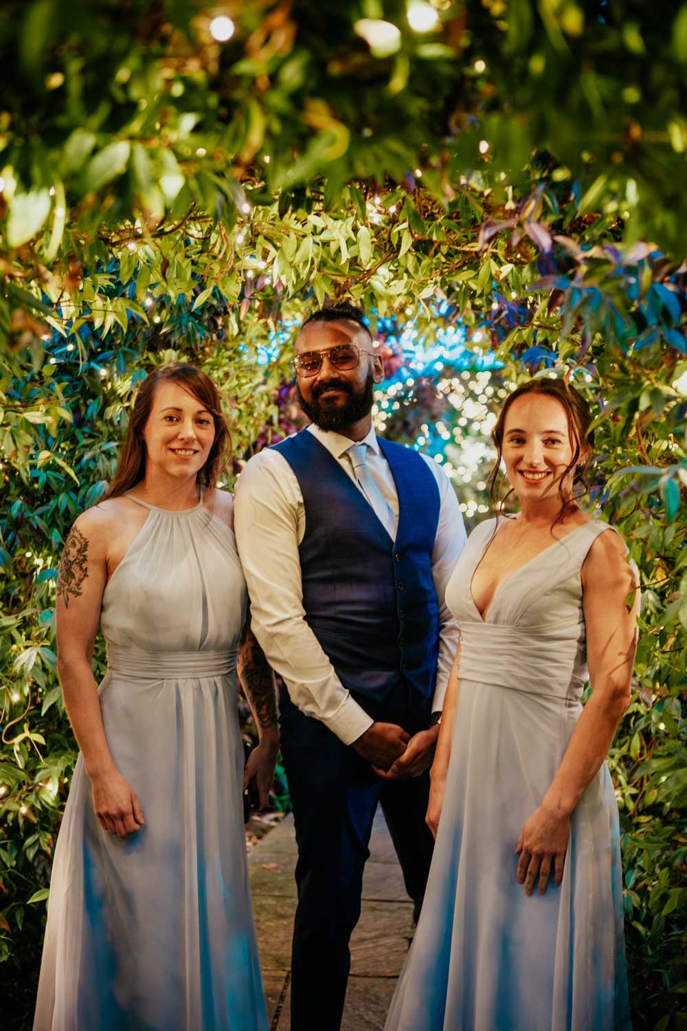 bridesmaids pose with groomsman under fairy lights in garden at Goosedale Nottingham