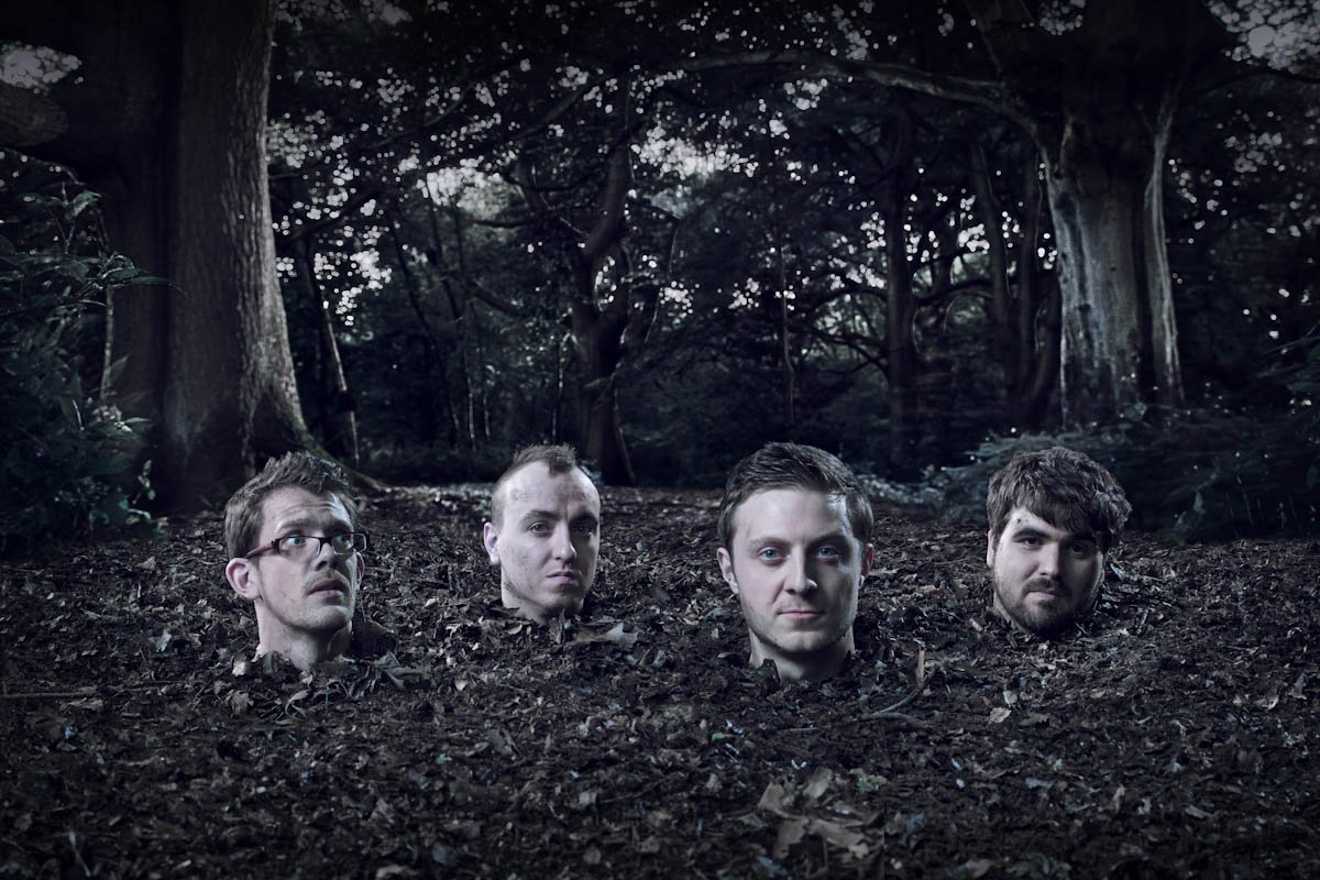 London band The Survival Code are buried up to their necks in the ground, in a forest at night