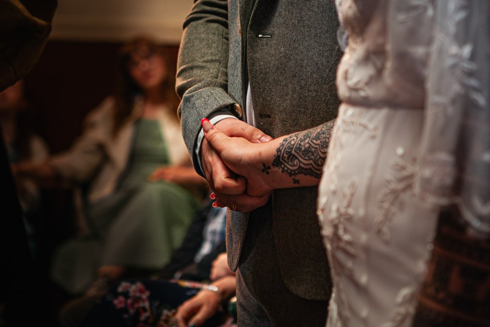 groom holds bride's tattooed hand in orthodox church ceremony