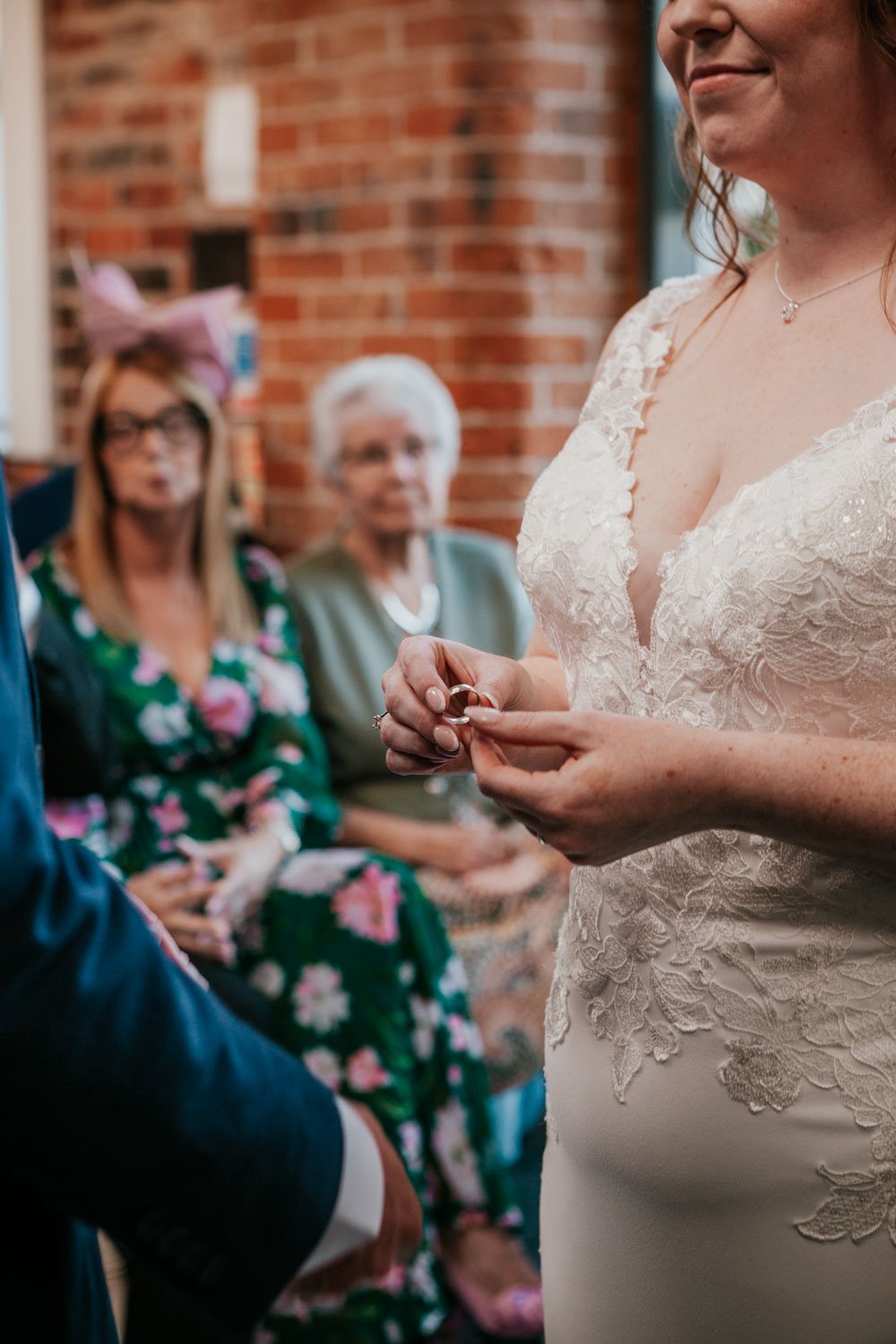 bride holds wedding ring, ready to place it on groom's finger