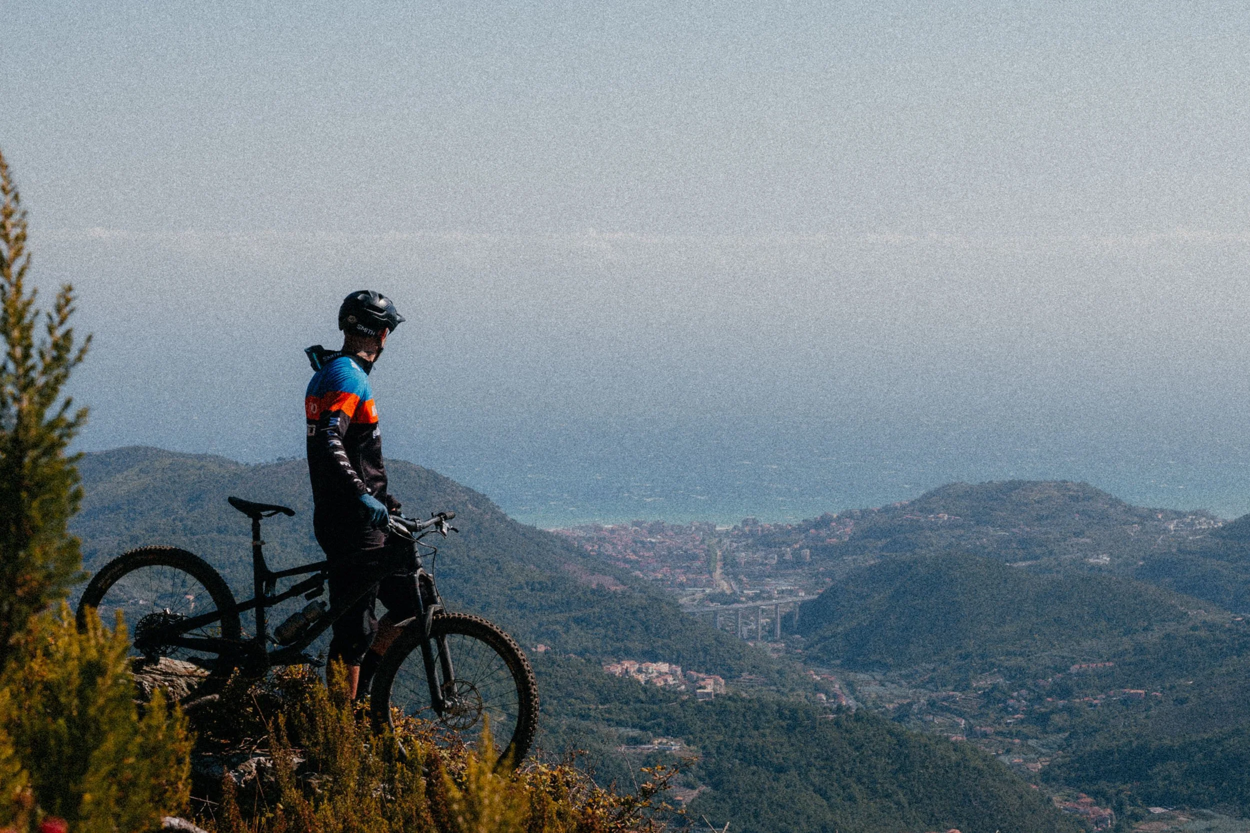 Mountain biker with bike overlooking scenic valley and coastline