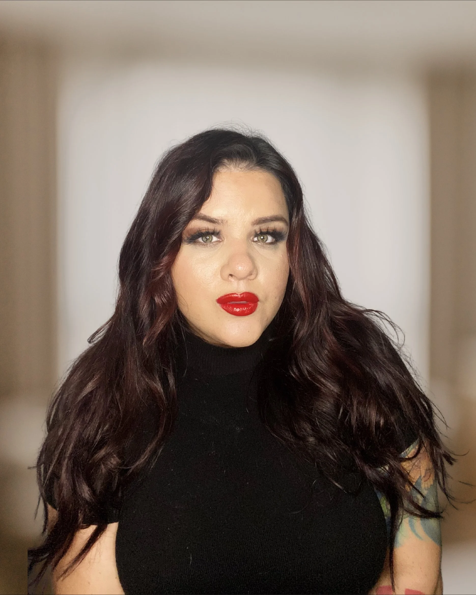 Person with dark hair and red lipstick in black top