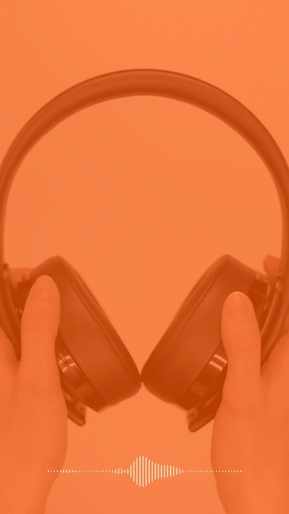 Person holding a pair of black over-ear headphones against an orange background.