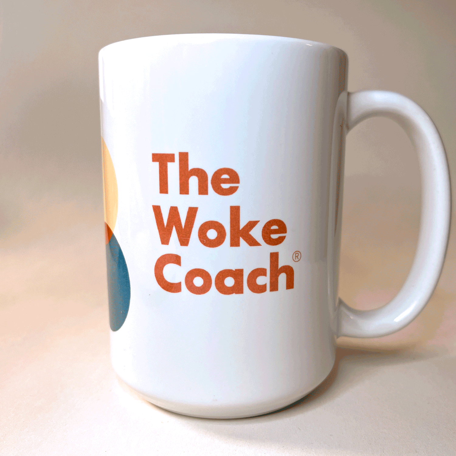 White ceramic mug with colorful design and the text 'The Woke Coach' in bold orange letters.