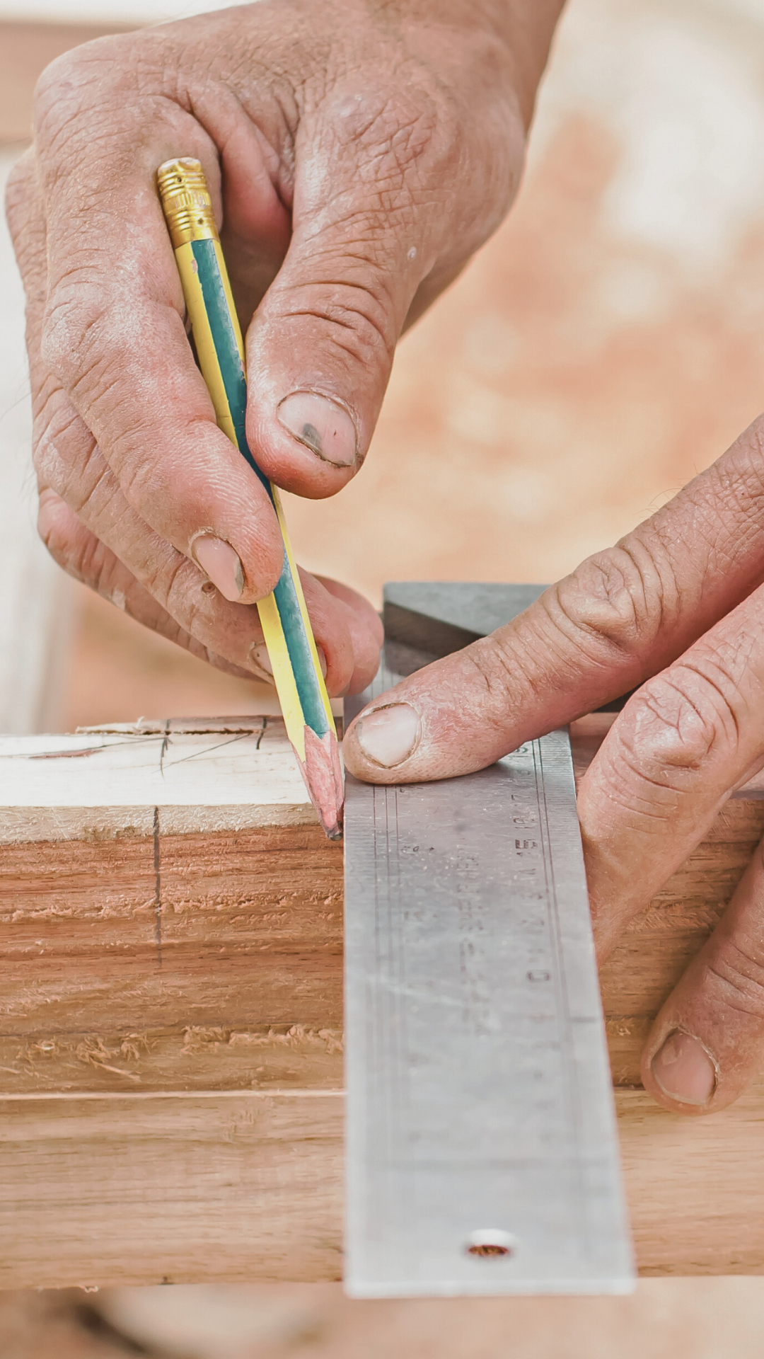 Carpenter marking lumber with a pencil and square