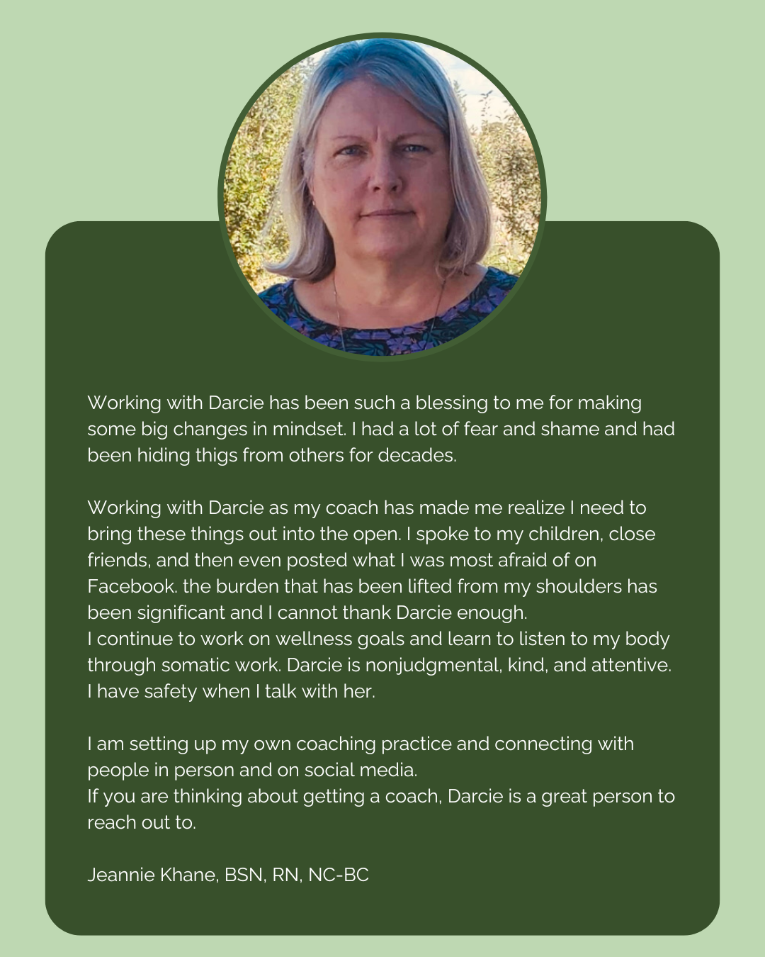 A woman with shoulder-length gray hair, wearing a blue floral top, standing outdoors with trees in the background.