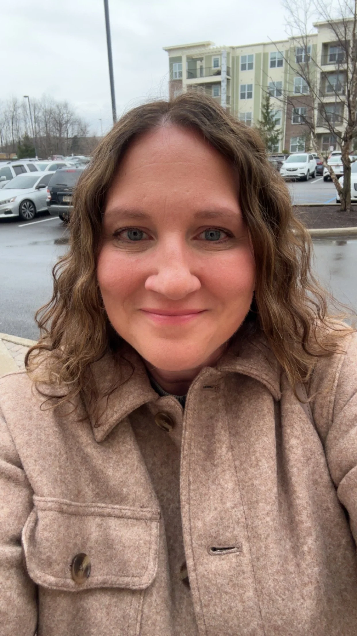 A woman with wavy light brown hair smiling indoors.