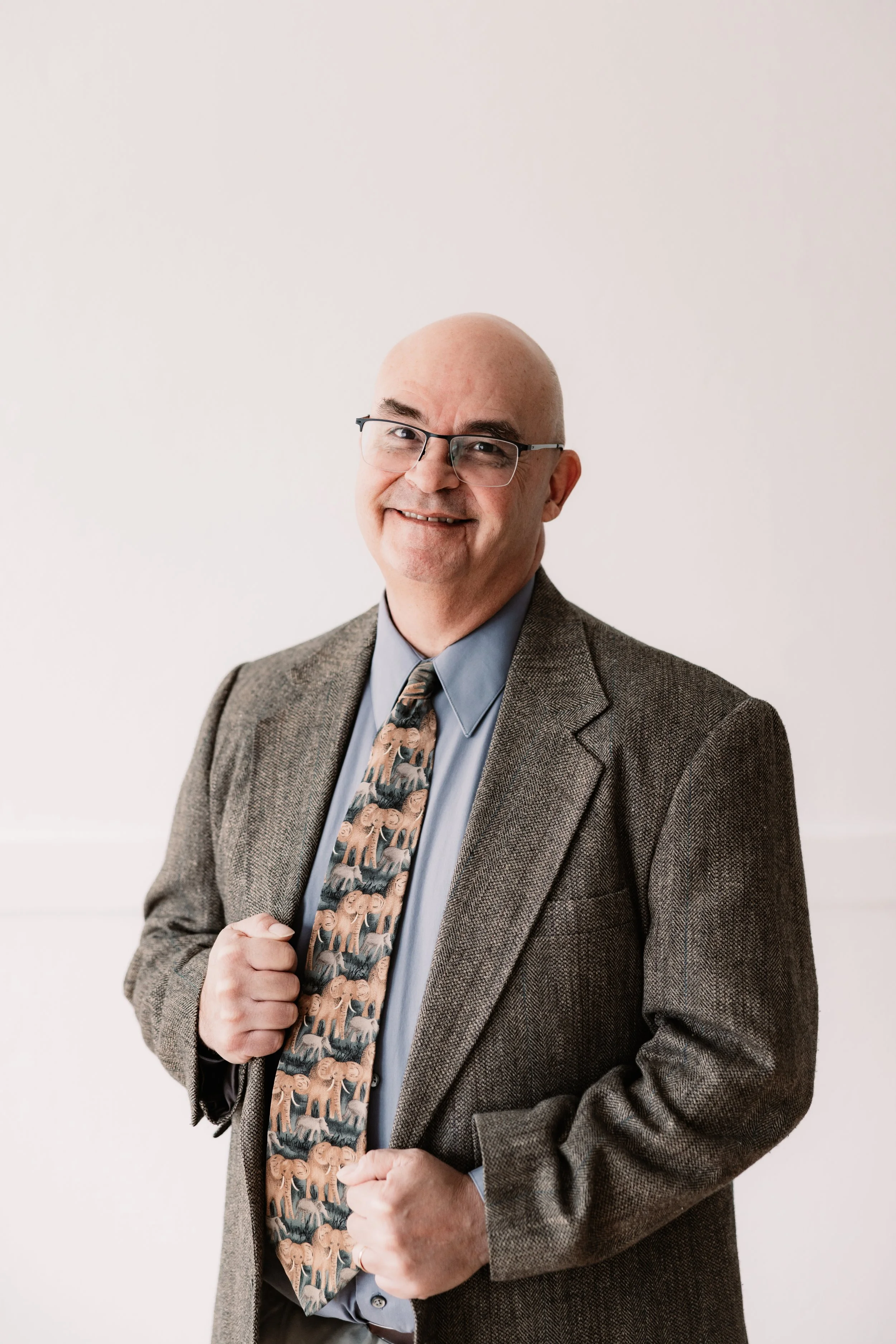 A smiling bald man wearing glasses and a light-colored collared shirt.