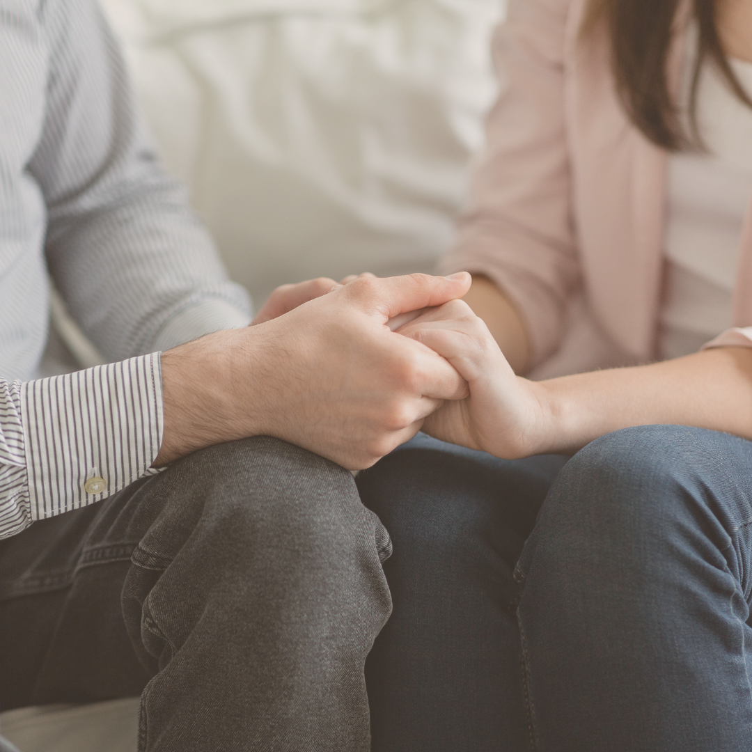 A person holding another person's hand in a comforting gesture.
