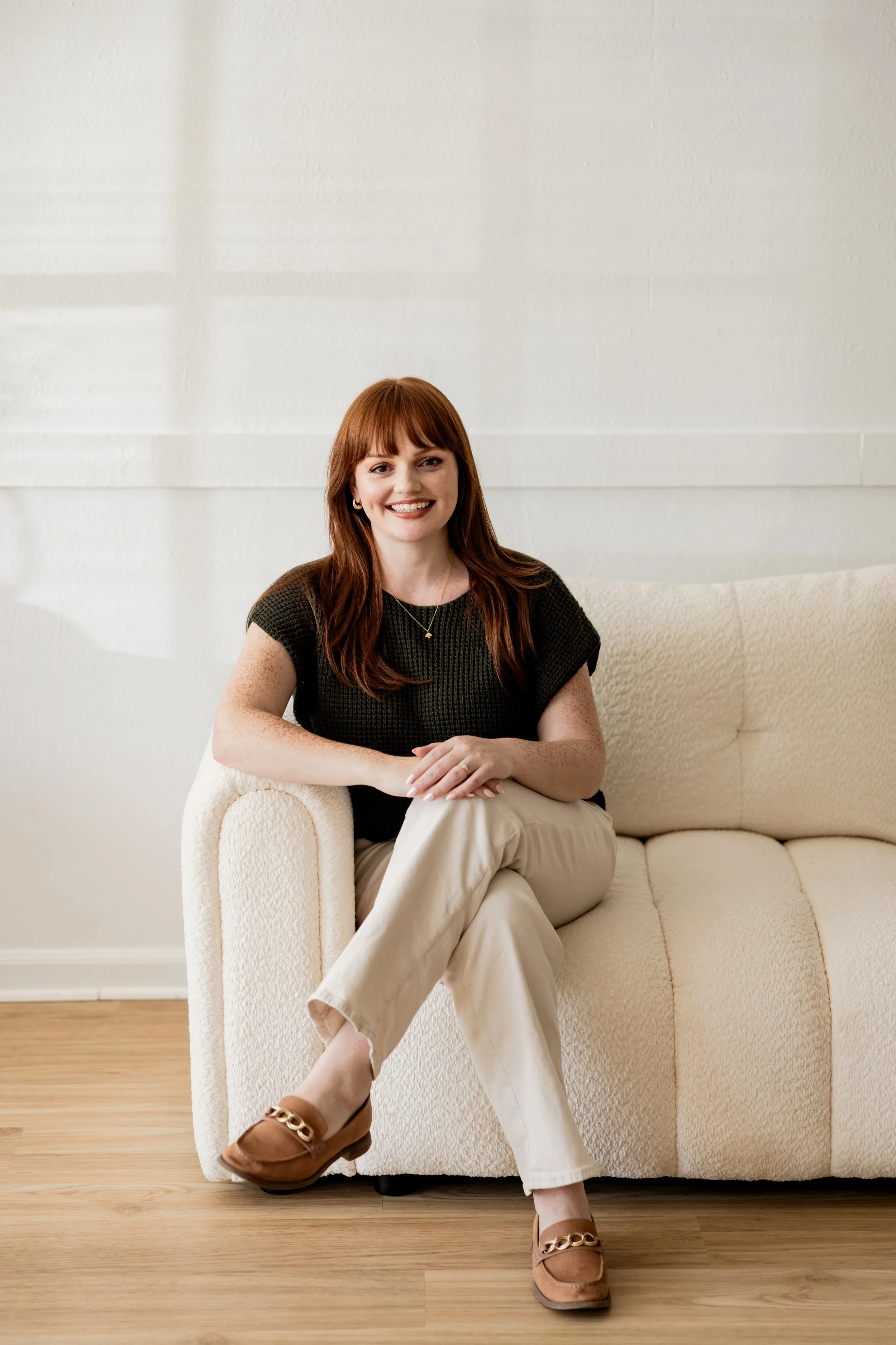 Headshot of a woman with red hair wearing a navy blazer and a blue and white patterned blouse, smiling at the camera.
