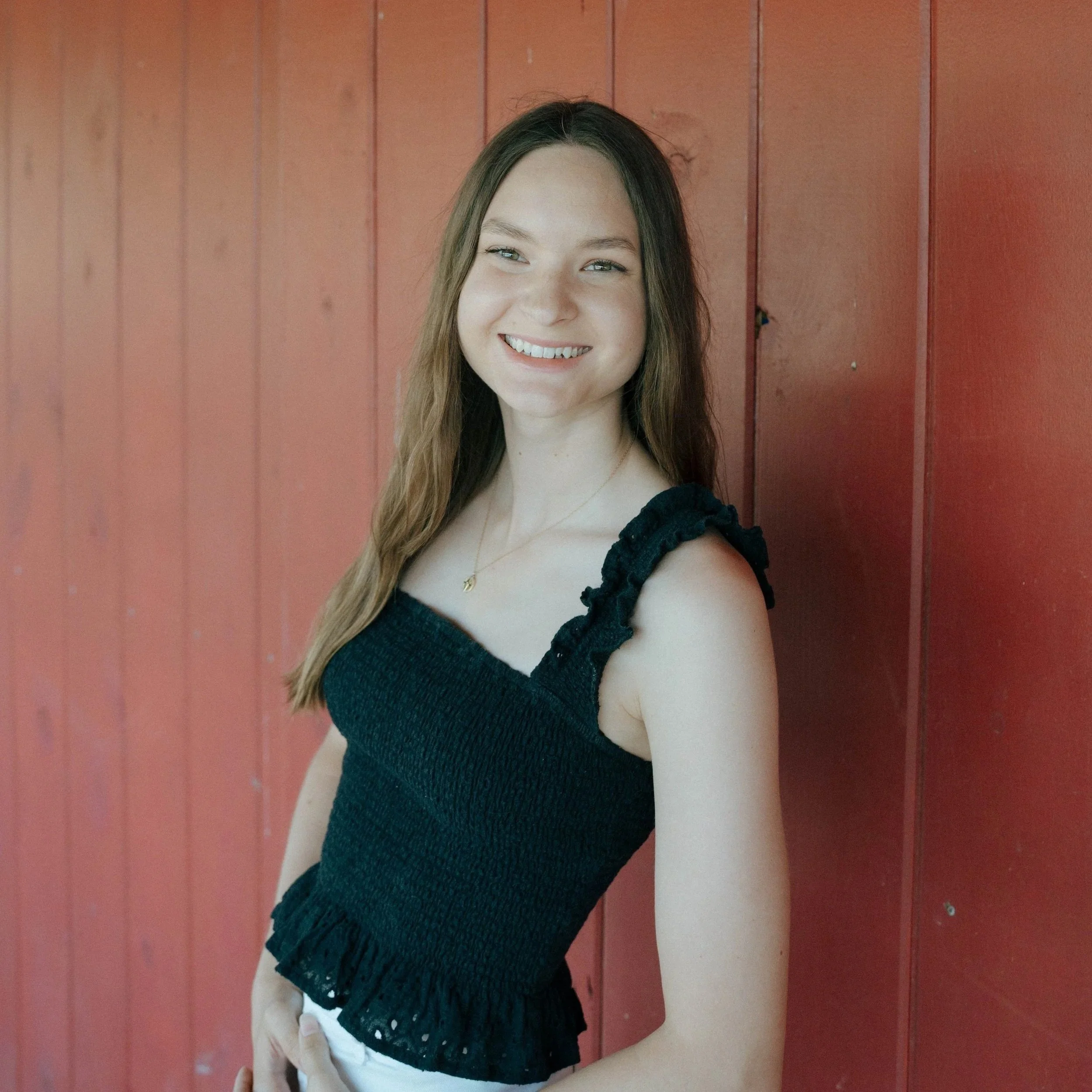 Smiling woman with brown hair wearing a light-colored blouse