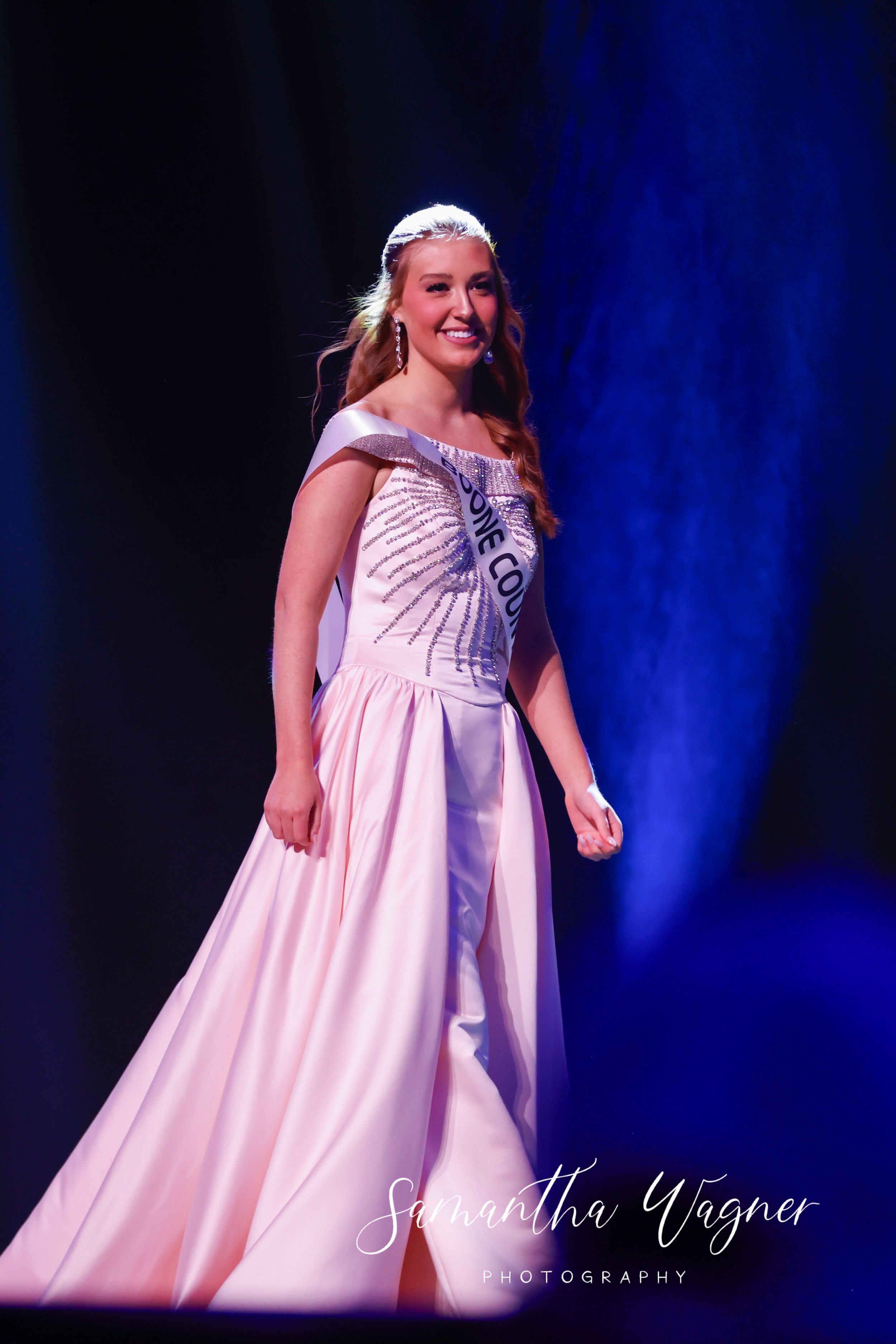 Beauty pageant contestant wearing a pink gown on stage.
