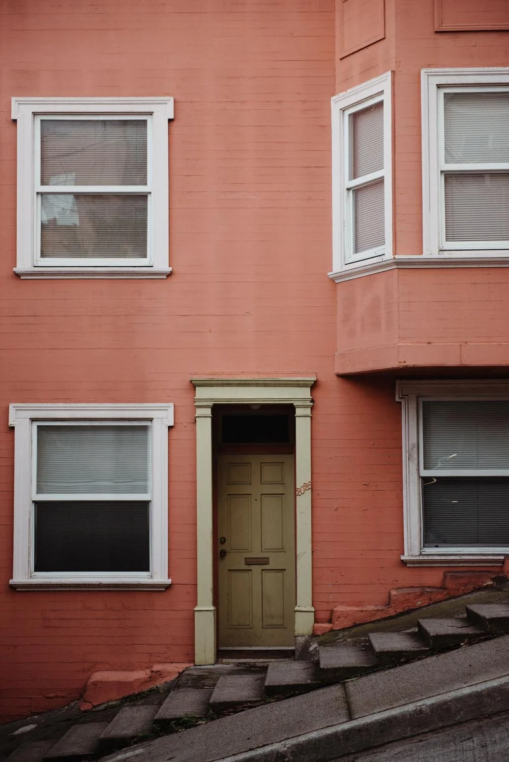 Close-up of an orange building on a sloped sidewalk.