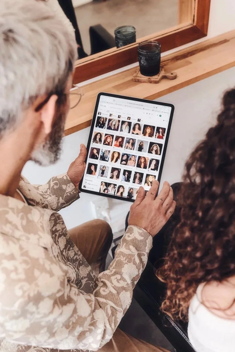 Curl consultation at Gato Loco, reviewing curly hair inspiration and shape references on a tablet before a curl transformation