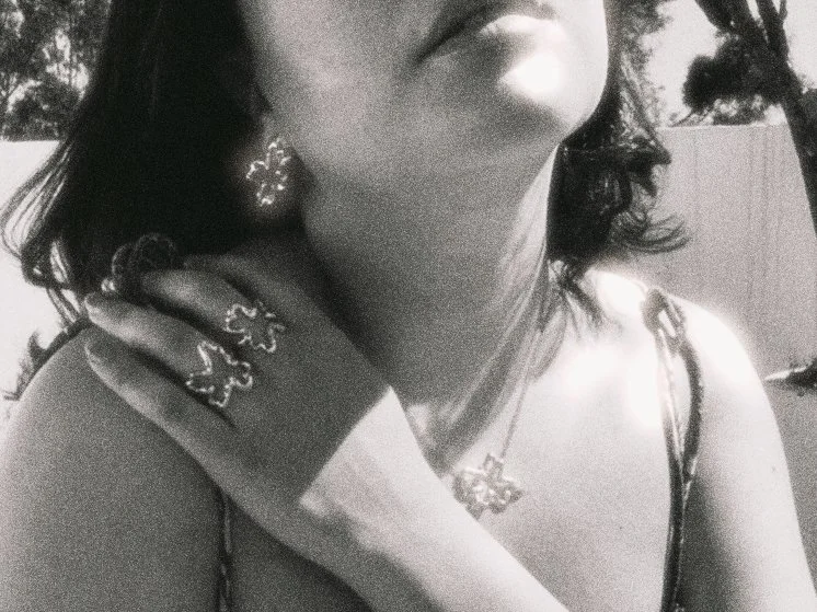 Mujer con accesorios de joyería, incluyendo aretes y anillos, en un entorno al aire libre.