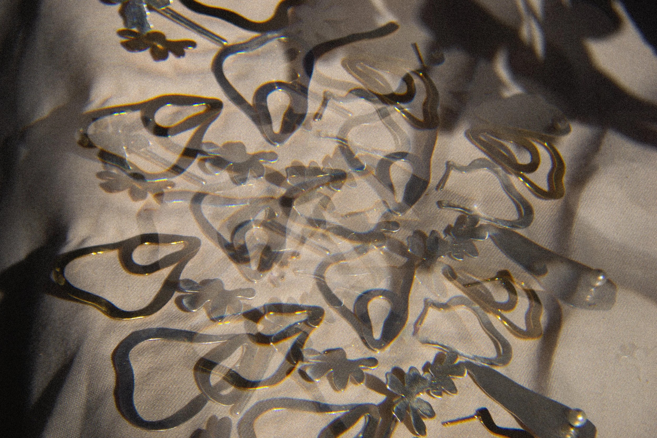 Lindas decoraciones en forma de flor y mariposa hechas con material transparente y detalles dorados sobre una tela blanca.