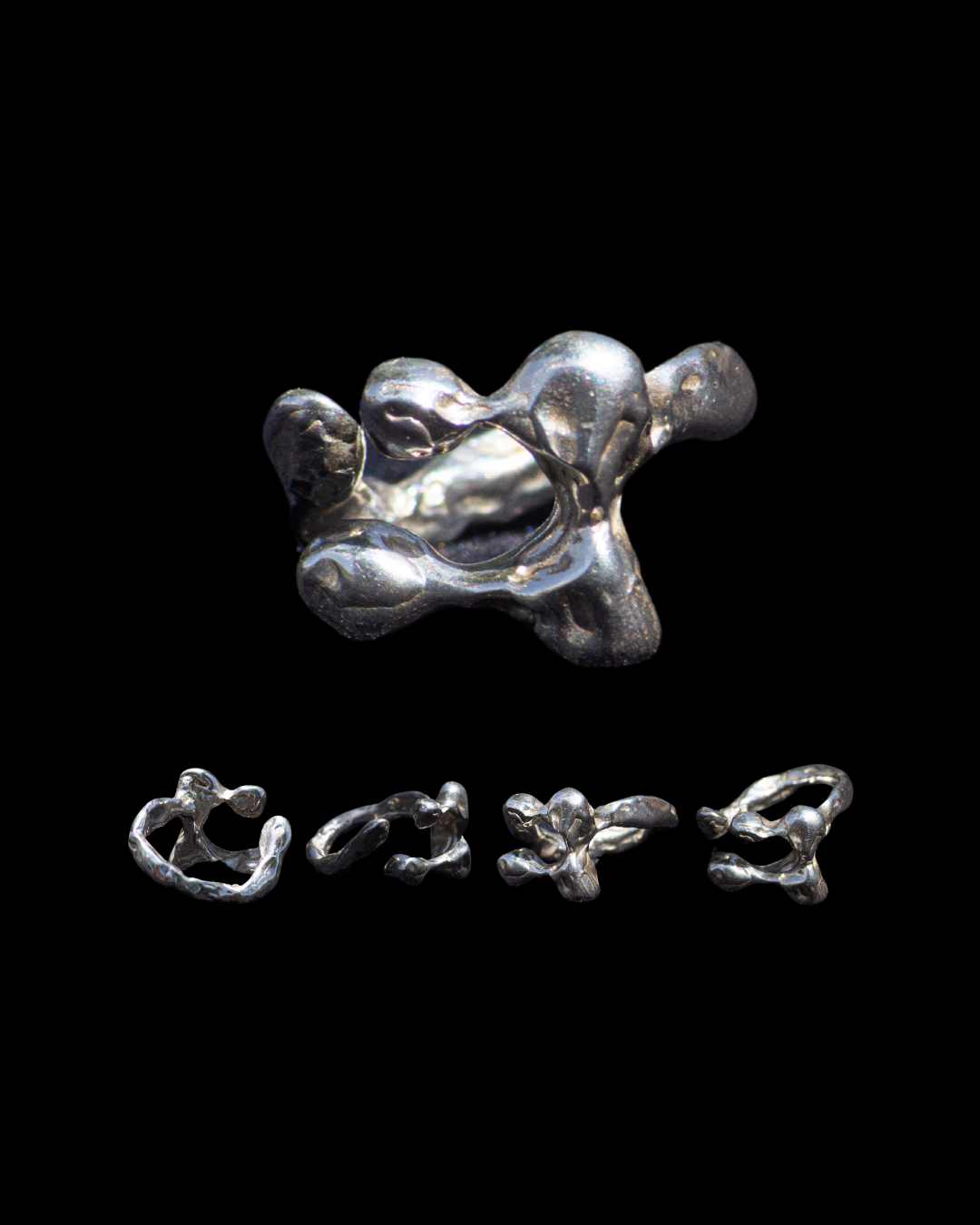 Esculturas de aluminio en forma orgánica y abstracta, con una pieza grande en la parte superior y varias pequeñas debajo, sobre fondo negro.