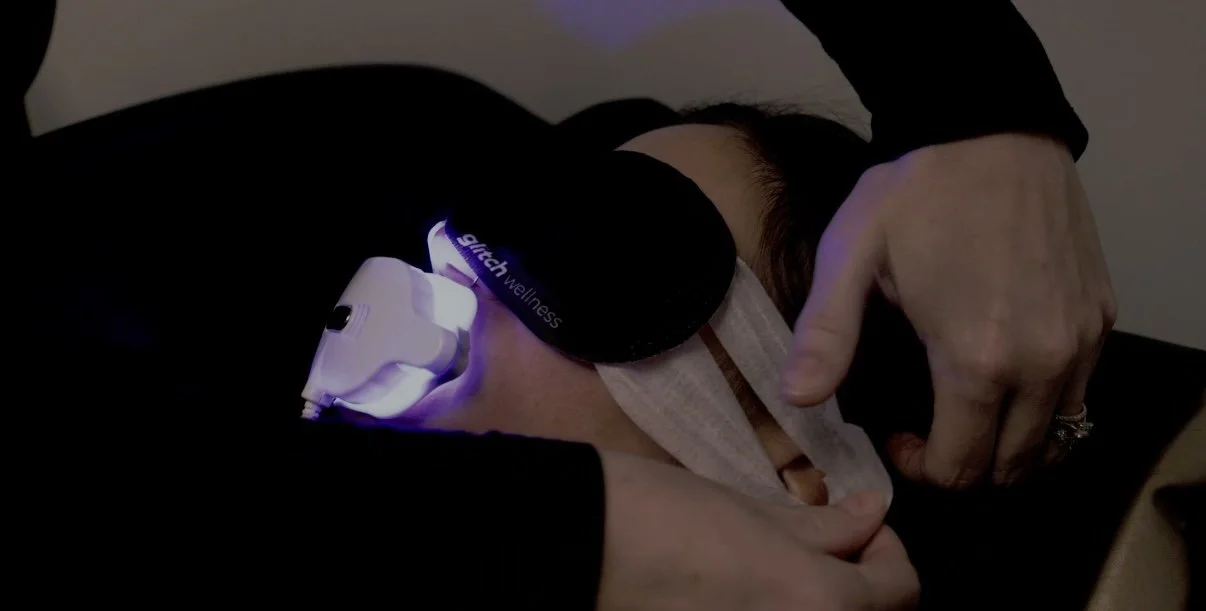 Teeth whitening specialist putting on the heated eye mask while client is under the LED teeth whitening light