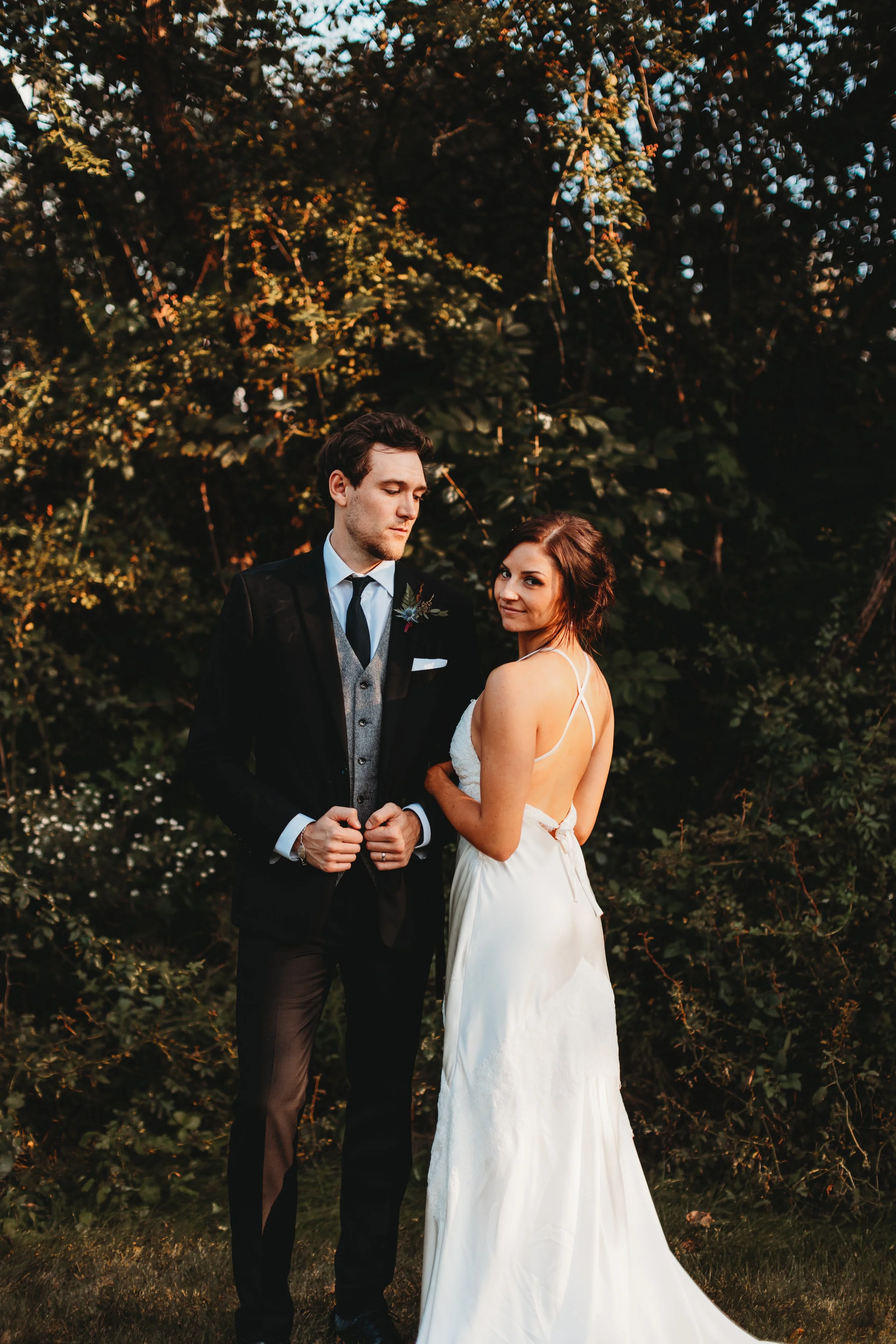 High fashion portrait of bride and groom. Groom looking down at bride, bride looking back to camera.