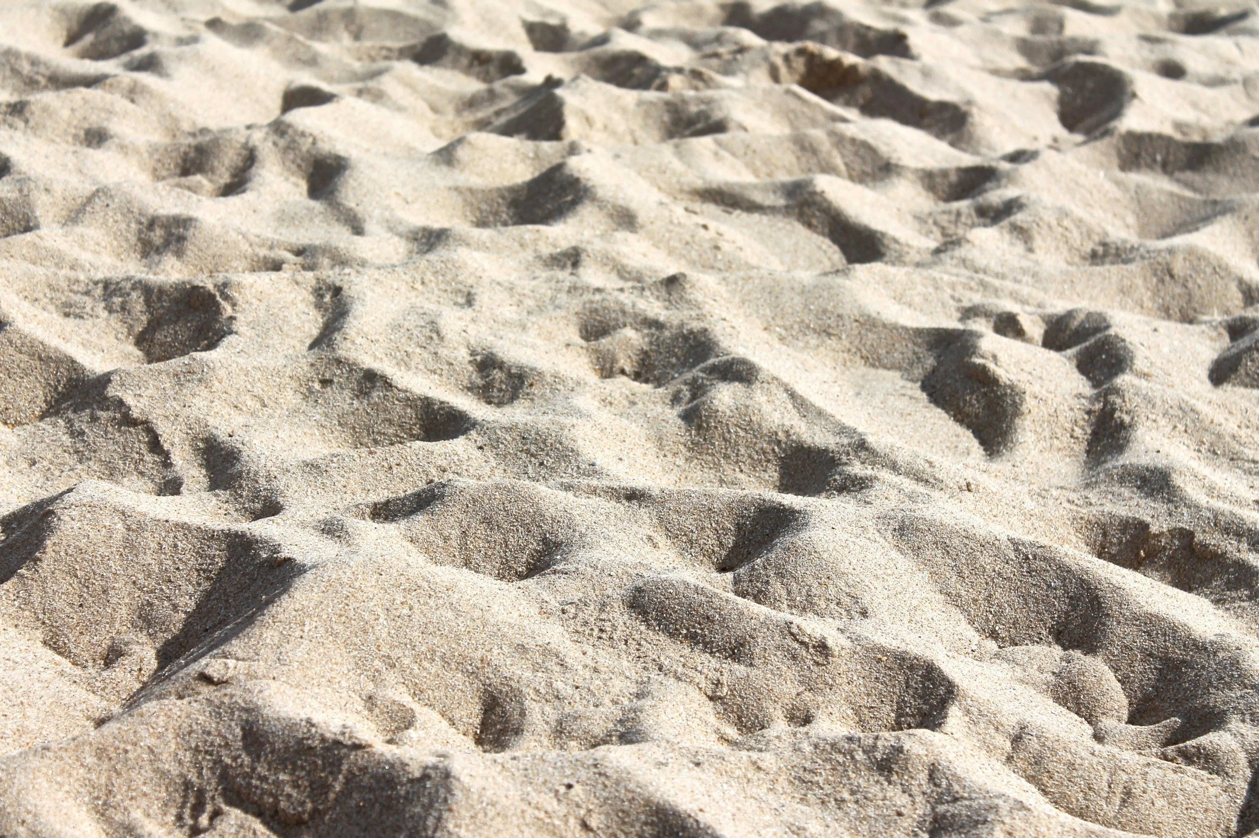 Close-up view of sandy beach with textured, rippled sand surface.