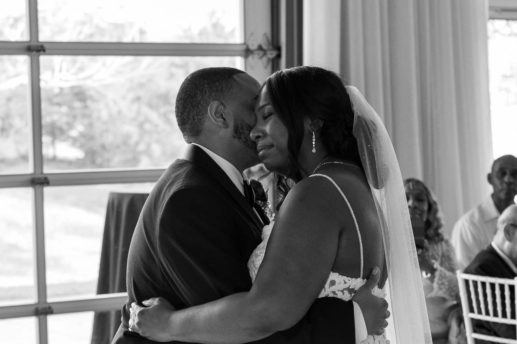 Bride and groom embracing during a wedding ceremony, black and white photo.