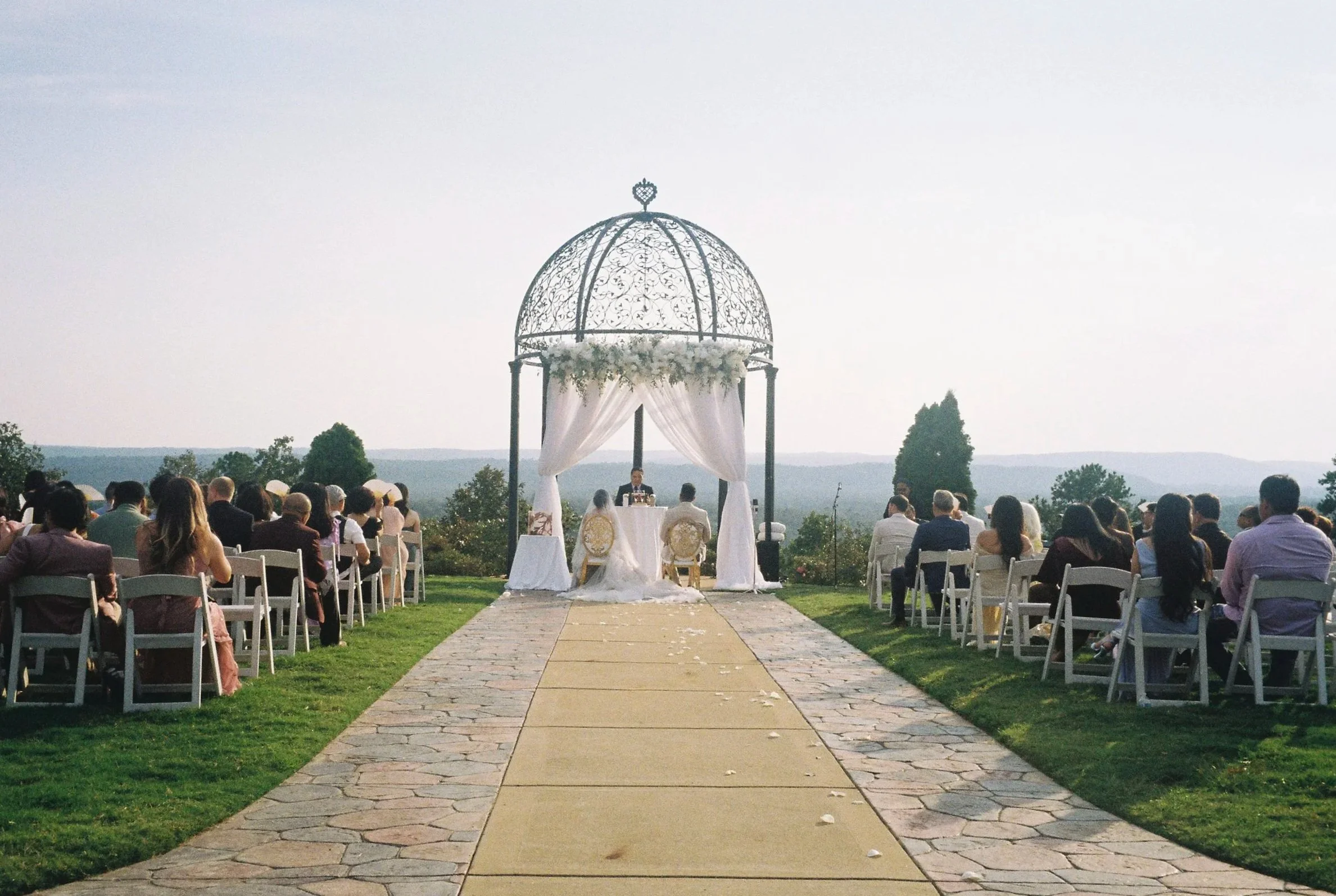 Young child in orange shirt and colorful hat playing with water and bubbles outdoors on a sunny day.
