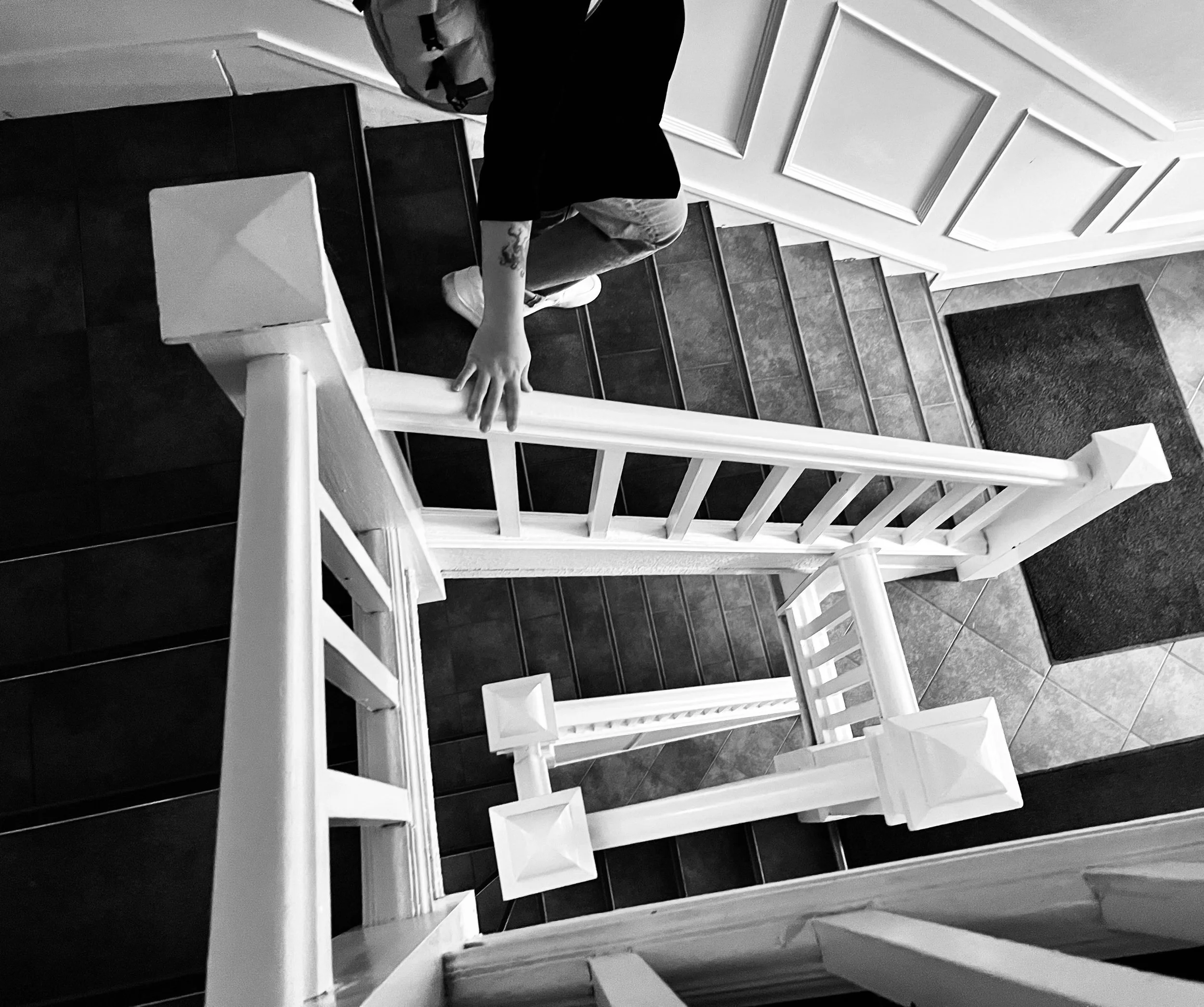 A person kneeling on stairs with their hand on the wall, seen from the side, in a black and white photo.