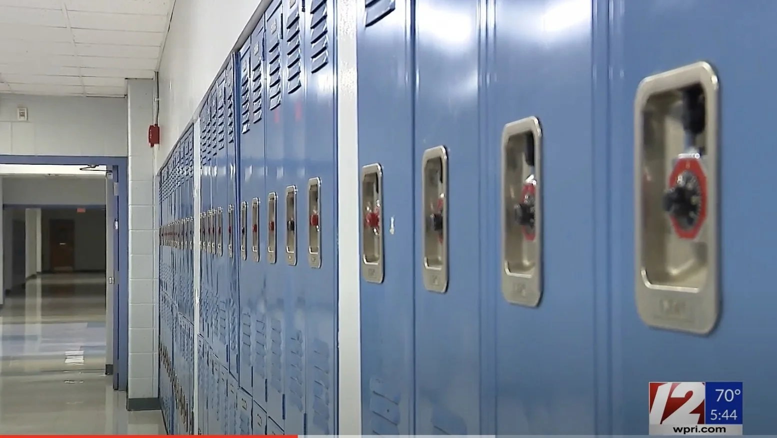 School hallway with blue lockers and a doorway at the end.