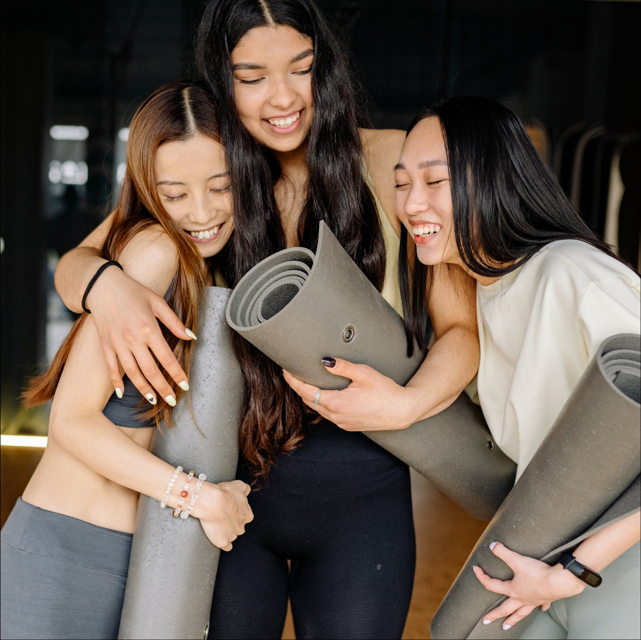 Community of women holding yoga mats, while smiling together.