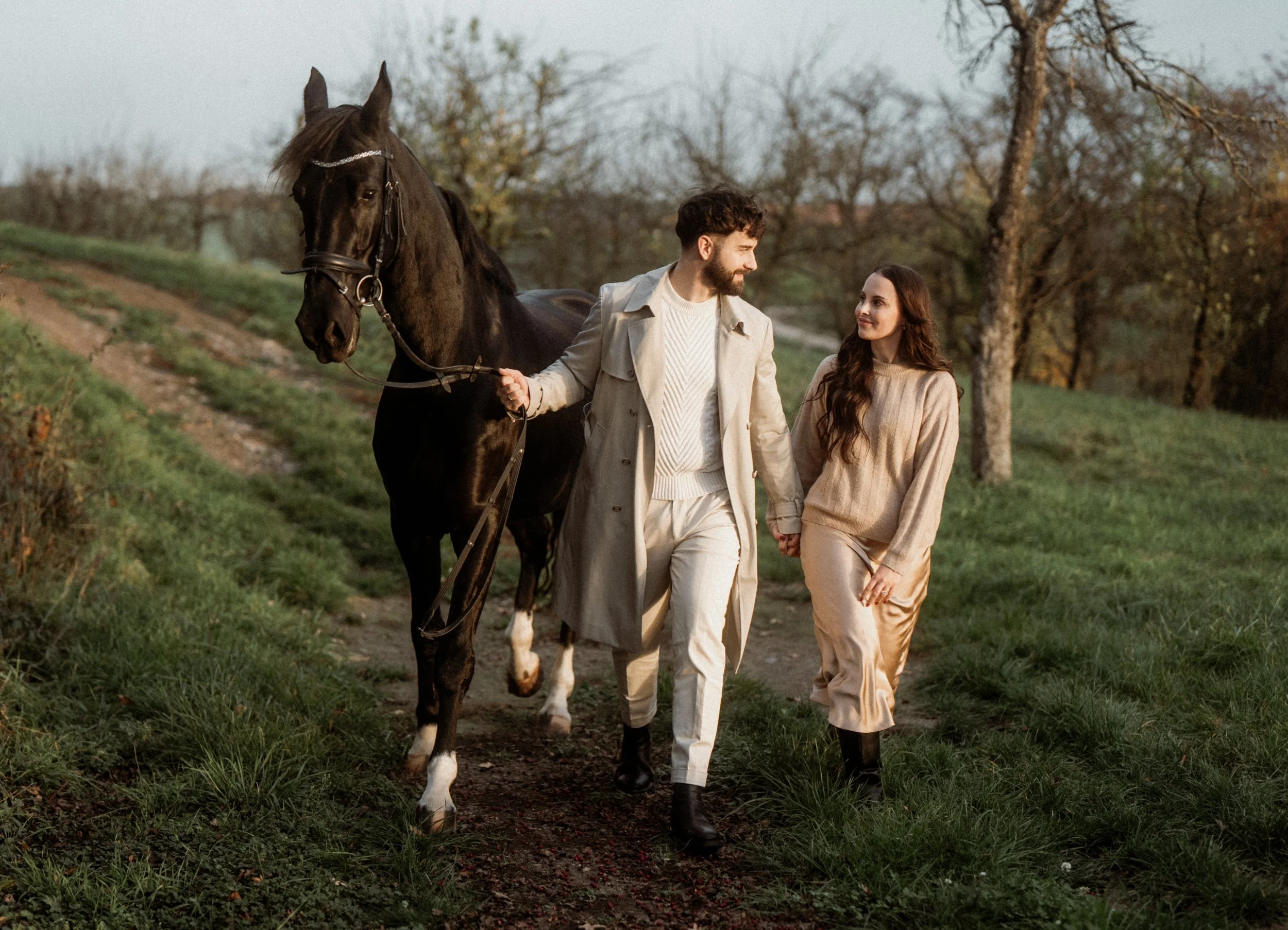 Ein Mann und eine Frau gehen Hand in Hand auf einem Weg im Grünen, begleitet von einem schwarzen Pferd. Paarshooting mit Pferd
Fotoshooting mit Pferd
Love Story 
Paarfotografie Baden-Württemberg
Paarshooting in der Natur
Romantisches Foto