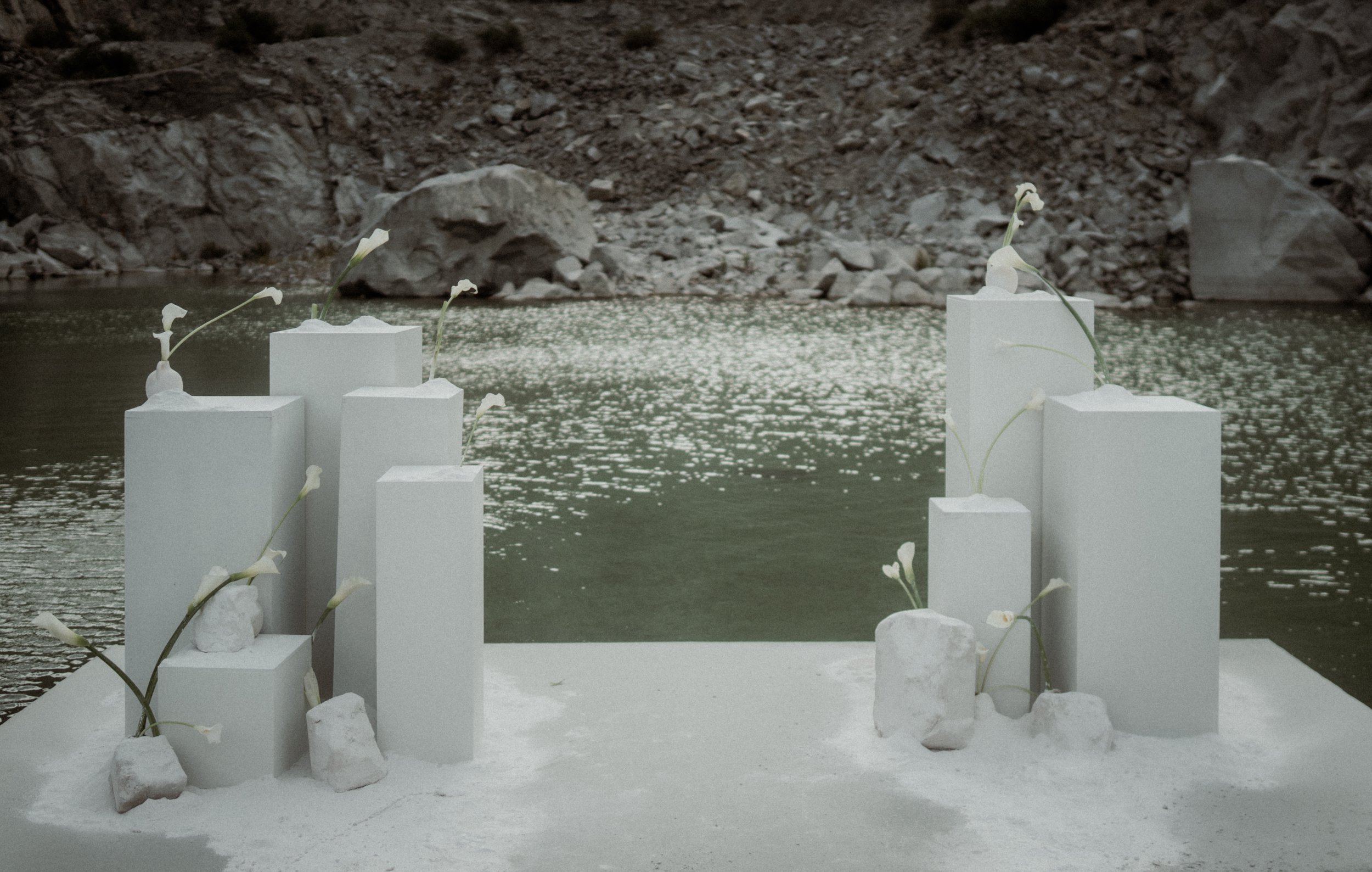 Trauungssteg auf dem See – moderne Elopement Zeremonie. Minimalistisches Setting für eine intime Hochzeit: ein weißer Steg führt zur Trauungsfläche mitten im See. Modernes Elopement-Konzept für Paare, die ihre Wedding-Zeremonie an einem besonderen Or