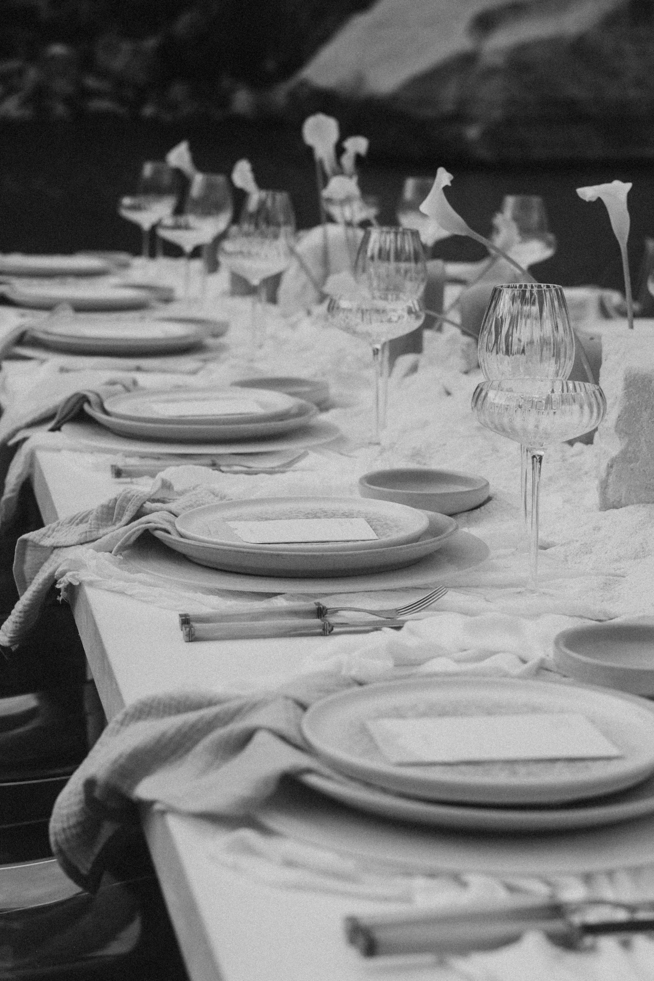Detail einer gedeckten Hochzeitstafel mit Gläsern und Calla-Akzenten – Elopement Detailshot einer Hochzeits-Tafel: Teller, Gläser, Textilien und florale Akzente im minimalistischen Stil. Ideal für Wedding-Details, Elopement-Feier und ästhetische Hoch