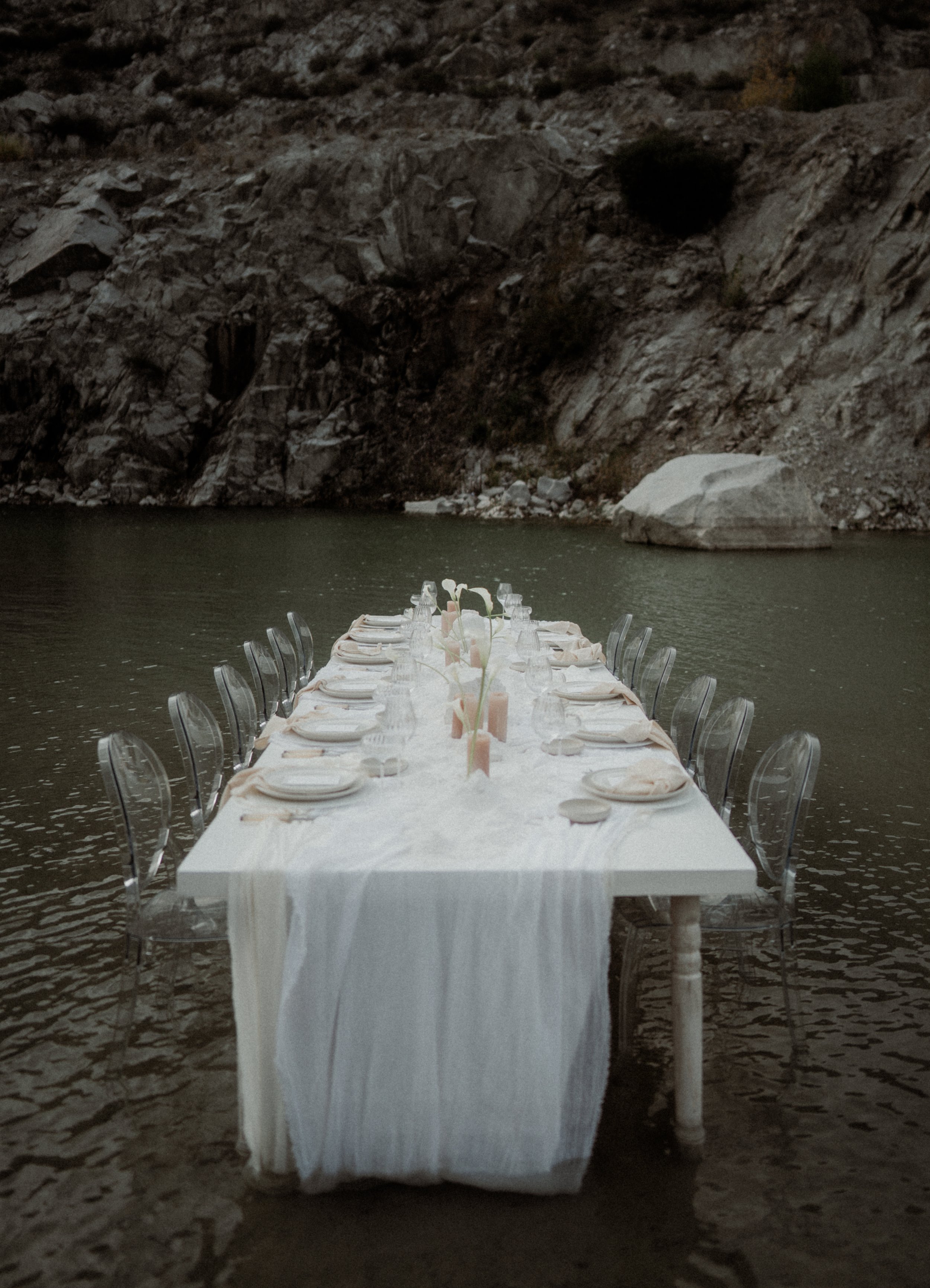 Lange festlich gedeckte Tafel im Wasser mit transparenten Stühlen – Elopement Hochzeitsfeier
Ungewöhnliche Hochzeitsfeier-Kulisse: eine lange, elegant gedeckte Tafel steht im Wasser, umgeben von Felsen. Perfekt für Elopement-Dinner, Wedding-Reception