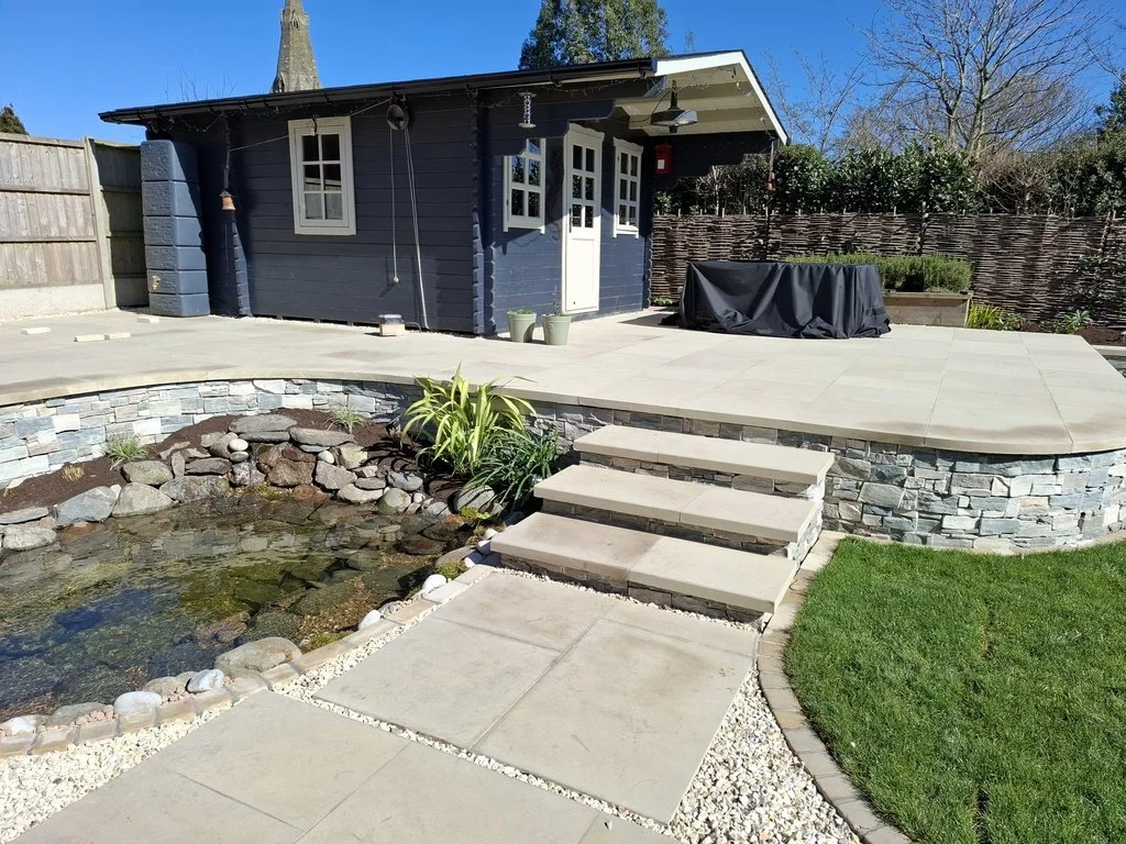 This garden needed a redesign to link the existing summerhouse with the new house extension, with new paving, steps and replacement pond and a reworking of the existing lawn and planting. The result is a generous entertaining space, a contemporary fe