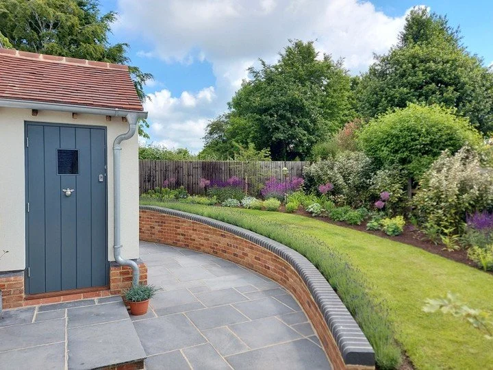 Making the most of a narrow strip of land to the side of this period property, we opted for a simple lawn pathway flanked by lavender hedge and cottage garden style planting, which sweeps round the porch, leading to the main garden beyond. Simple but